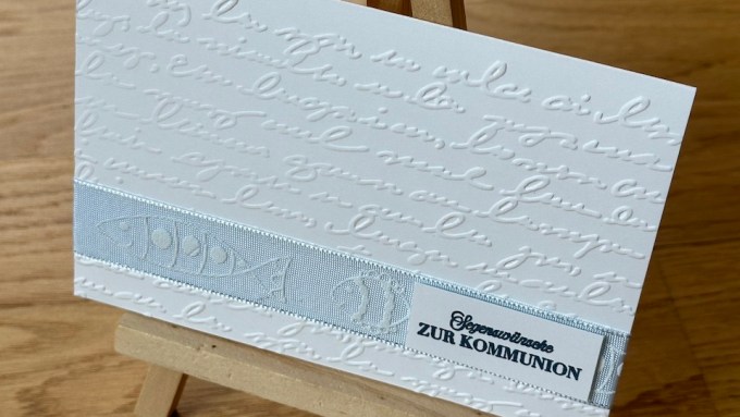 Selbstgebastelte Karte zur Kommunion in weiß mit hellblauem Band und Prägung