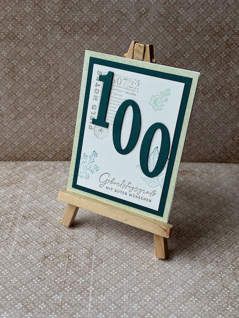 Gebastelte Geburtstagskarte mit mittgrüner Grundkarte und Smaragd-Layer, weißer Deckseite mit Eckstempel, grünen Blüten und Blättern am Rand, Variante mit Zahlen 70 und 100, handgefertigtes Unikat.