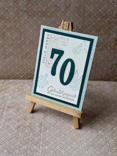 Gebastelte Geburtstagskarte mit mittgrüner Grundkarte und Smaragd-Layer, weißer Deckseite mit Eckstempel, grünen Blüten und Blättern am Rand, Variante mit Zahlen 70 und 100, handgefertigtes Unikat.